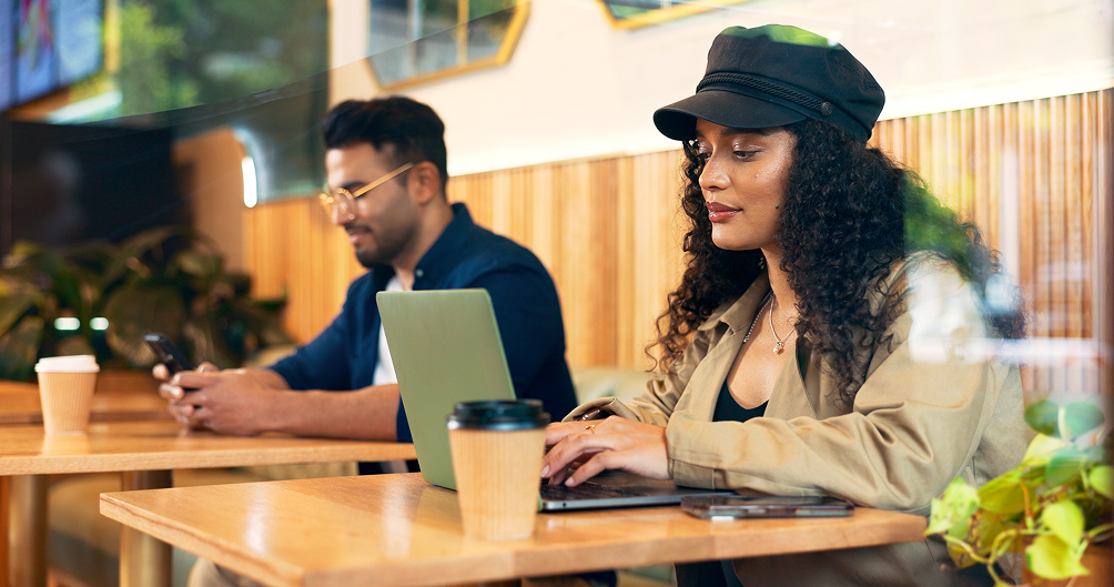 Two individuals working on their devices in a coffee shop